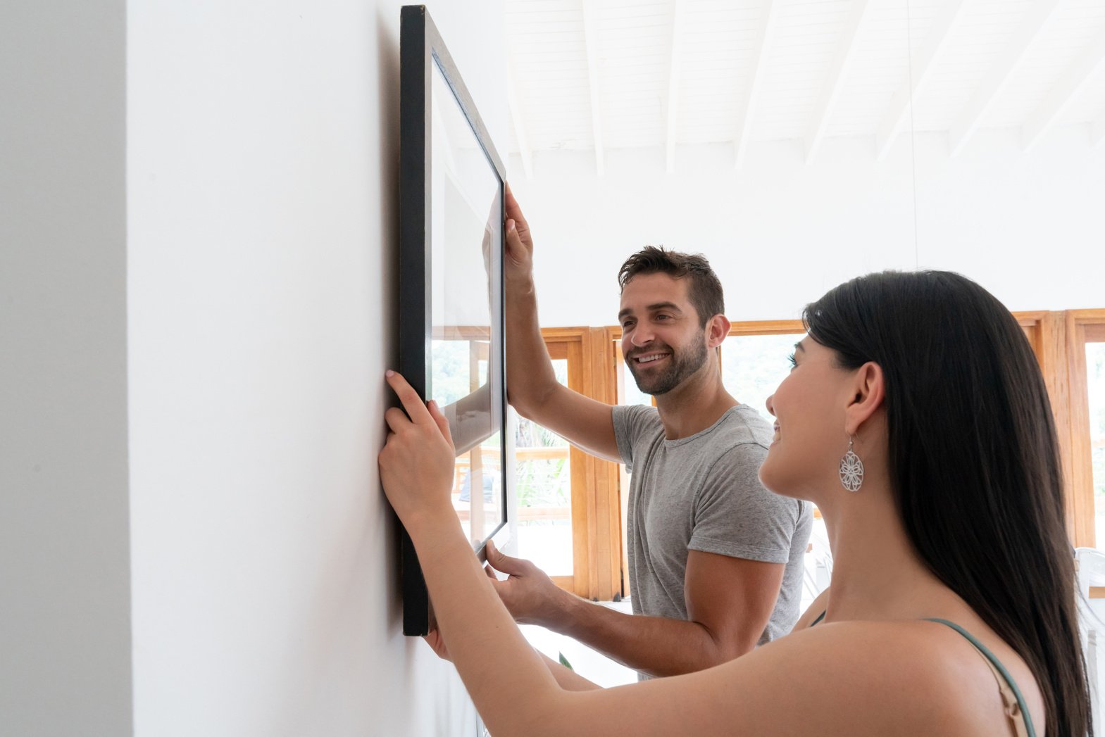 Loving couple hanging a picture together at home