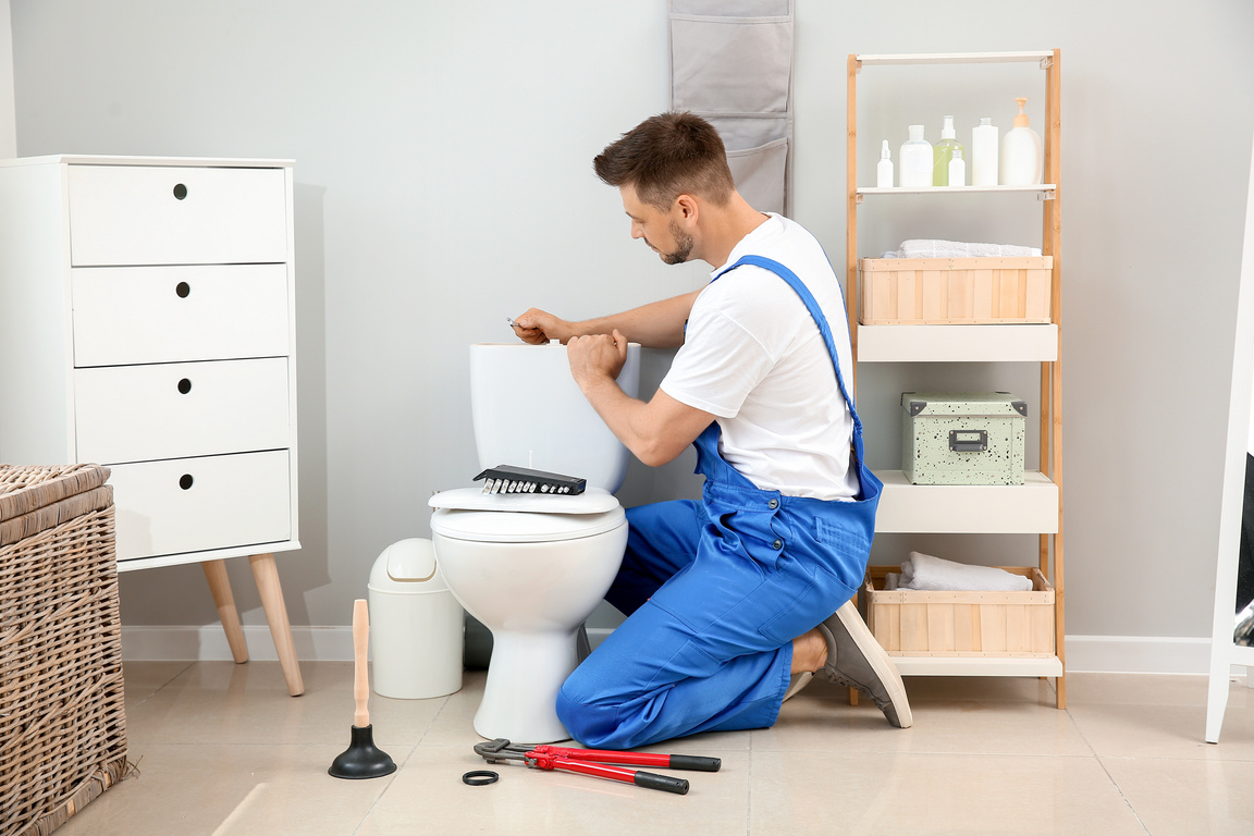 Plumber Installing Toilet in Restroom